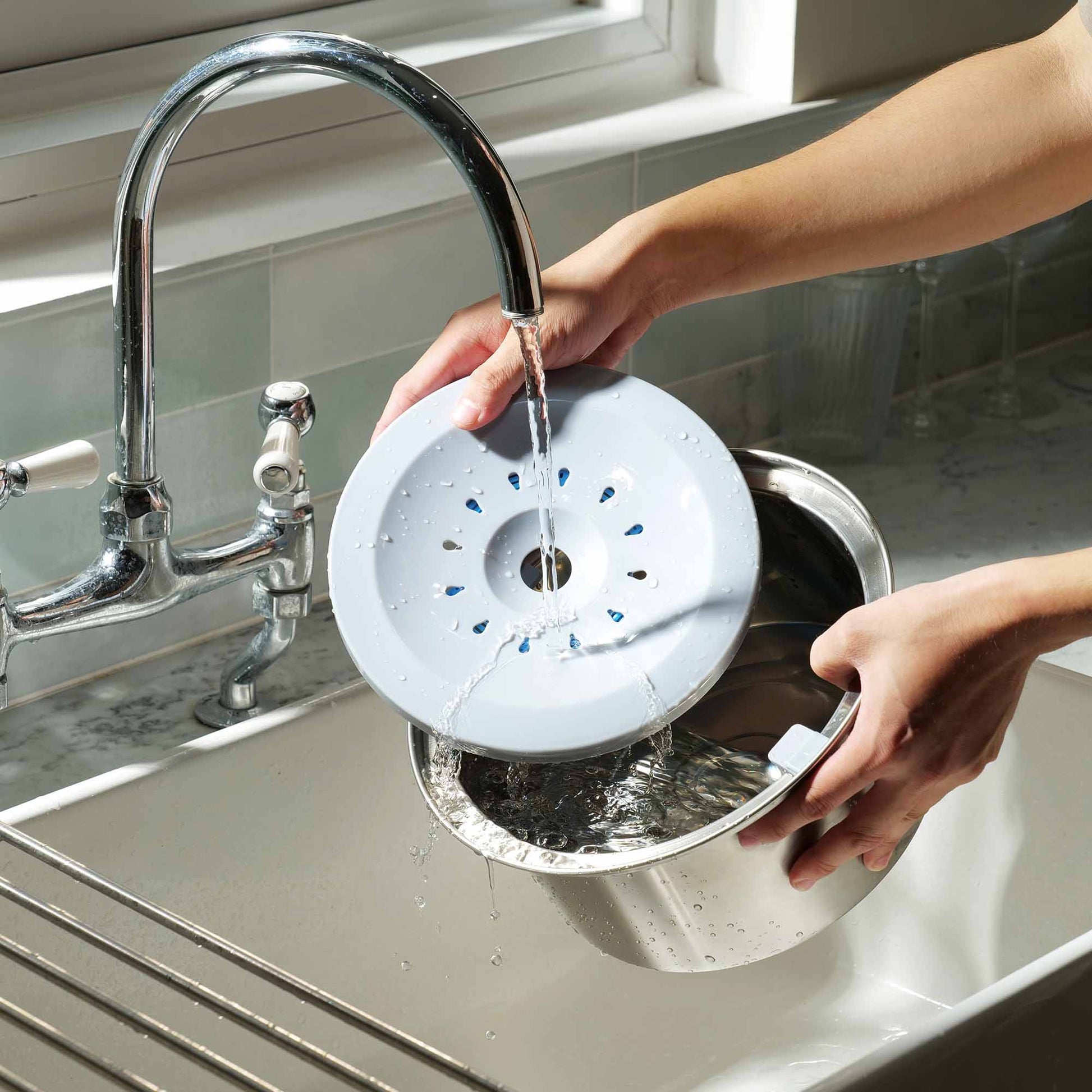 Person rinsing the floating plate of PuppHub's Zero Splash Ultra bowl in a sink.