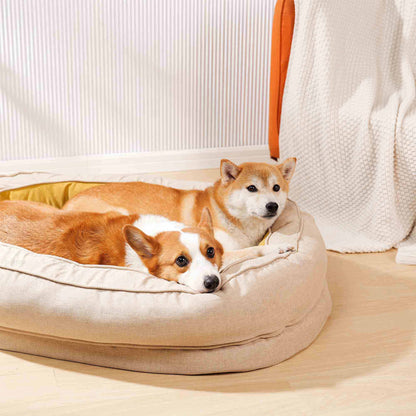 Corgi and Shiba Inu lounging in a plush beige dog bed with yellow filling.